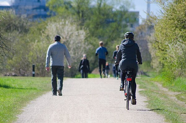 Velofahrer und Fussgänger in einem Park.