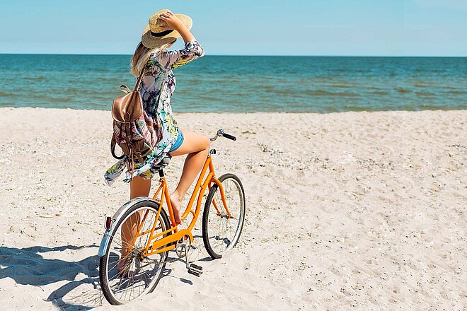 Frau mit Fahrrad am Sandstrand