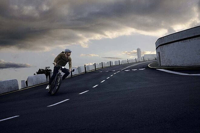 Stromer tritt der Coalition for Cyclist Safety in den USA bei. In Mann fährt mit dem E-Bike auf einer Strasse. Dunkle Wolken am Himmel.