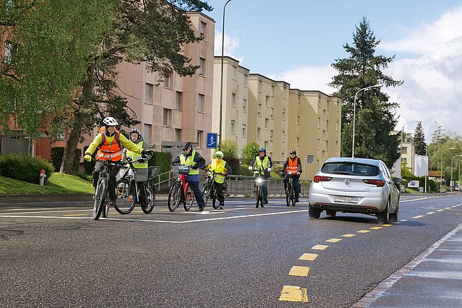 E-Bike Fahrkurse Kursanbieter Schweiz. Eine Gruppe Radfahrer mit Leuchtwesten auf der Strasse.