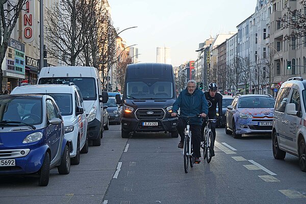 Zwei Radfahrer auf einer dicht befahrenen Strasse in Berlin.