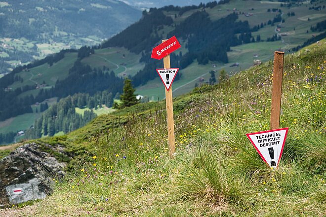 Swiss Cycling. Mountainbike Trail in Lenzerheide. Wegweise auf grüner Wiese in den Alpen.