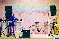 DJ steht for Wand mit Graffiti, am Rand des Bildes steht ein Fahrrad