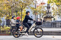 BH Monty Bikes Longtail Cargobikes aus Spanien. Eine Frau fährt mit einem Lastenrad durch die Stadt.