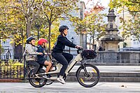 BH Monty Bikes Longtail Cargobikes aus Spanien. Eine Frau fährt mit einem Lastenrad durch die Stadt.