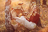 Mädchen neben Velo im Laub. 