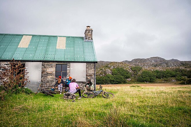 Endura B-Corp B-Labs. Eine Gruppe vom Menschen sitzt mit Mountainbikes auf einer Wiese.