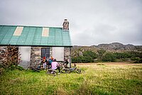 Endura B-Corp B-Labs. Eine Gruppe vom Menschen sitzt mit Mountainbikes auf einer Wiese.