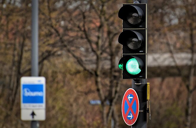 Grüne Ampel mit Baum im Hintergrund
