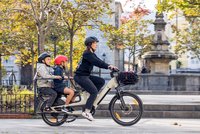 BH Monty Bikes Longtail Cargobikes aus Spanien. Eine Frau fährt mit einem Lastenrad durch die Stadt.