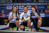 Nathalie Schneitter gewinnt E-Mountainbke Weltmeisterschaft. Drei Frau in Radsportkleidern knien für ein Foto und halten Medaillen in den Händen.