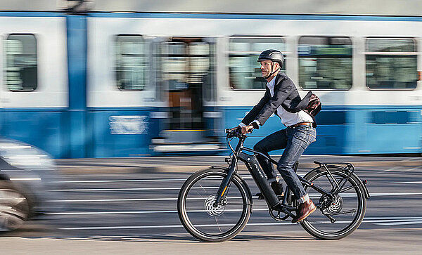 Ein Mann mit Helm fährt in der Stadt auf einem E-Bike.