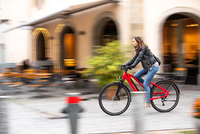 Eine E-Bikerin fährt durch die Stadt.