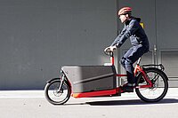 Ein Mann fährt auf einem roten Riese & Mülller Packster 70 Lastenvelo