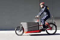 Ein Mann fährt auf einem roten Riese & Mülller Packster 70 Lastenvelo