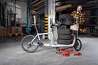 Cargobikes im professionellen Einsatz. Ein Mann lädet Autoersatzreifen auf ein Lastenrad.