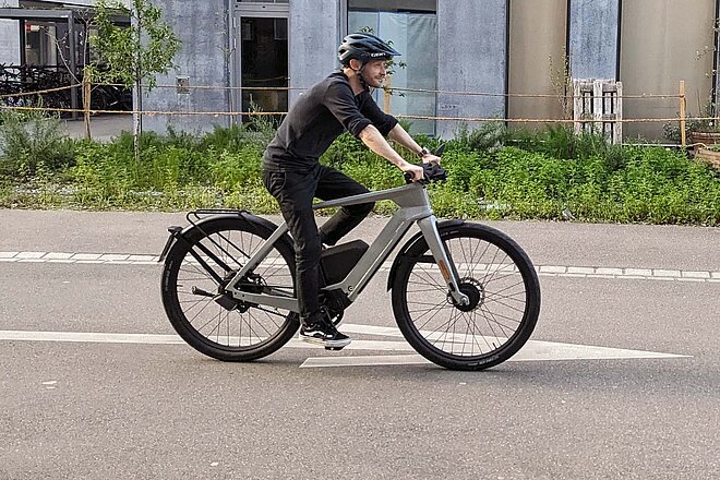 Specter 1: Long Range Test. Ein Mann fährt mit dem E-Bike auf einer Strasse. 