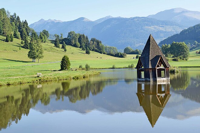 Dramatische Gebirge, lange Flussläufe mit Radrouten, sanfte Hügel, Kultur und Lebensfreude im Süden. Das und mehr bietet die Steiermark. Wer sich auf die Reise macht, wird reich belohnt. (Foto: Dres Balmer) Ein Kirchturm ragt aus dem Wasser.