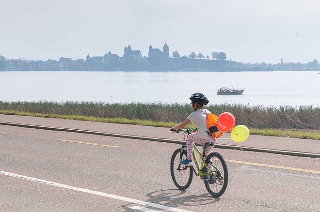 Slowup Zürichsee Autofreier Tag. Ein Kind fährt mit dem Velo auf der Strasse. Am Fahrrad sind Ballone befestigt.