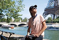 Velostadt Paris. Ein Mann mit pinkem T-Shirt sitzt auf einer Mauer an der Seine.