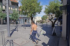 Ein Mann trägt ein Surfbrett unter dem Arm.