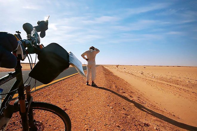 Eine Person steht mit dem Fahrrad in der Wüste