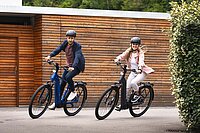 Das ABC der E-Bike-Begriffe. Eine Frau und ein Mann fahren auf E-Bikes um eine Kurve.