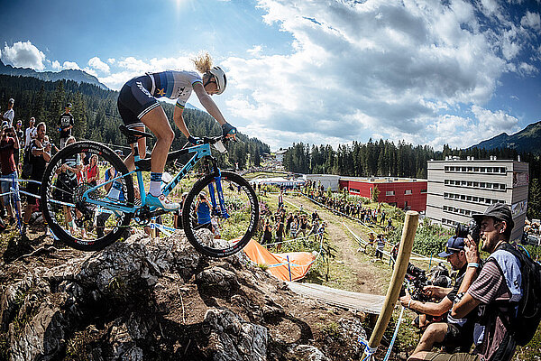 Eine Frau fährt mit dem Mountainbike über ein Hindernis.