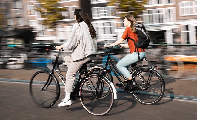 zwei Frauen fahren mit Hollandrädern durch Amsterdam. E-Bike Unfälle in Holland.