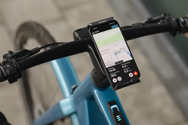 Smartphone mit eBike Flow App von Bosch am Lenker eines E-Bikes.