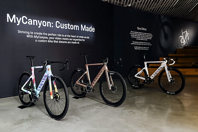 Rennräder stehen vor einer schwarzen Wand.