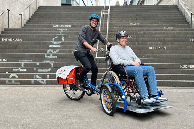 Ein Dreirad-Pedelec samt Fahrer und Gast.