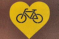 Gelbes Herz mit einem Velosymbol in der Mitte.