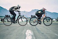 Zwei Radfahrer sitzen mit Motorradbekleidung auf Velos.