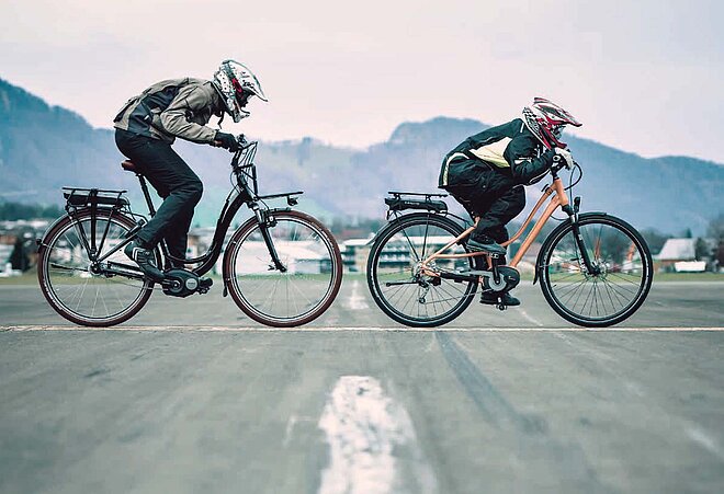 Zwei Radfahrer sitzen mit Motorradbekleidung auf Velos.