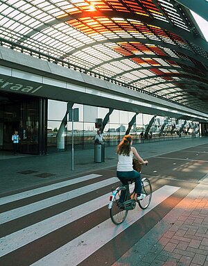 Eine Frau fährt auf einem breiten Radweg in Amsterdam mit dem Velo