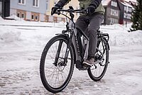 Eine Person fährt auf einer verschneiten Strasse mit dem Elektrovelo