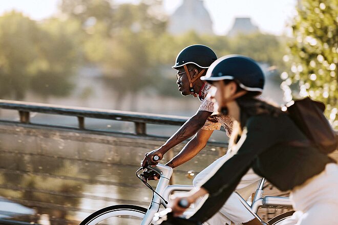 Eine Frau und ein Mann fahren mit Fahrrädern. Beide tagen schicke Kleider