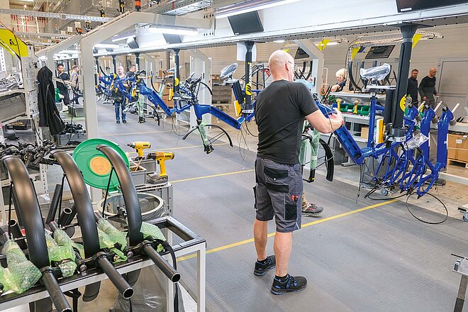Ein Mann in kurzen Hosen und T-Shirt arbeitet an einem Fahrrad.