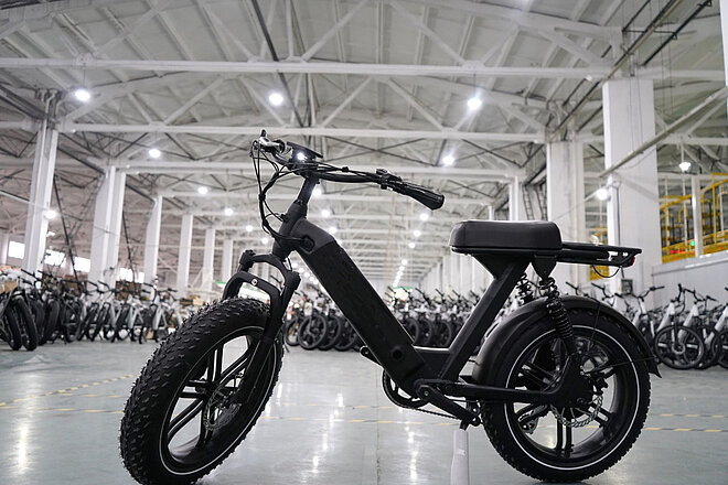 Ein E-Bike mit dicken Reifen und schwarzem Rahmen steht in einer Lagerhalle.