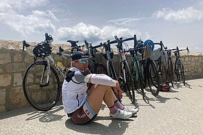 Eine Rennradfahrerin sitzt am Boden vor mehreren Rennvelos