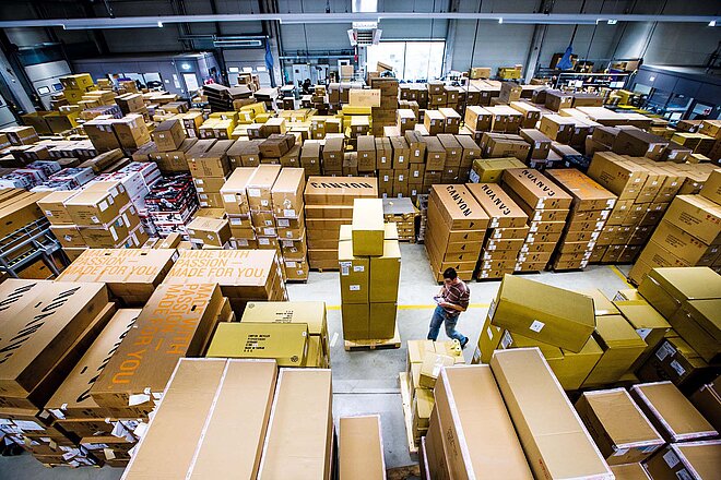 Der deutsche Veloversender Canyon hat zwei neue Investoren an Bord. Ein Mann läuft durch eine Lagerhalle, in der viele Fahrradkartons stehen.