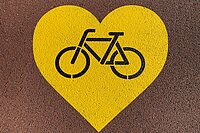 Gelbes Herz mit einem Velosymbol in der Mitte.