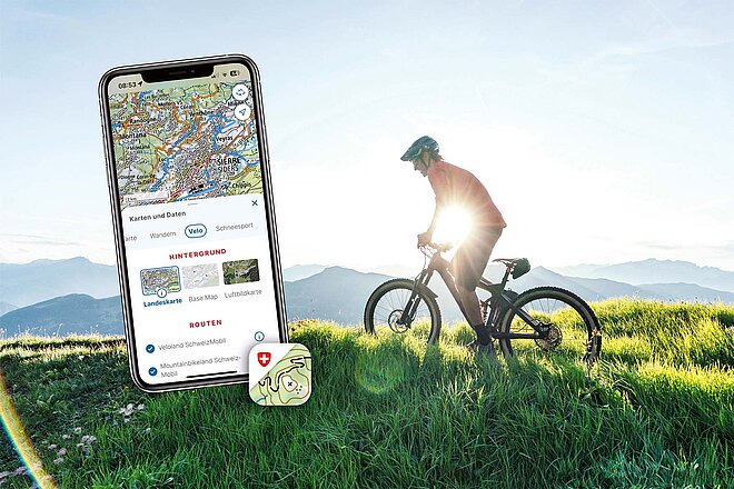Mit der Swisstopo-App haben Sie alles im Griff. Ein Mountainbiker fährt über ein Feld.