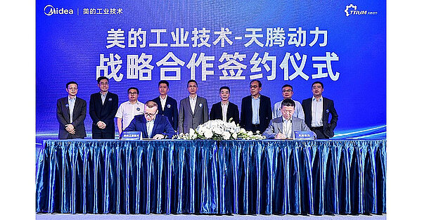 Bei der zeremoniellen Unterzeichnung der Übernahme wurde kein Aufwand gescheut. Männer stehen stramm in Anzug und Krawatte.