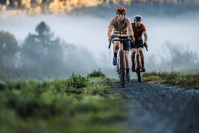 Strava Year in Sport 2023. Eine Frau und ein Mann fahren auf Gravelbikes auf einer Schotterstrasse.