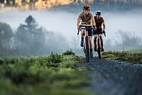 Strava Year in Sport 2023. Eine Frau und ein Mann fahren auf Gravelbikes auf einer Schotterstrasse.