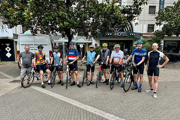 Gruppetto. Radfahrer stehen nebeneinander auf einem Platz.