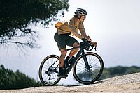 	Ein Mann mit beigem Hemd fährt auf einem Gravelbike.