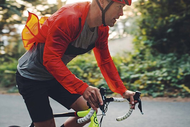 Vista Outdoor trennt das Unternehmen auf. Ein Mann fährt mit einer rotern Jacke und rotem Helm auf einem Rennrad.